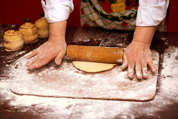 Close up of female baker hands kneading dough and making bread with a rolling pin. Cooking Process Concept 
