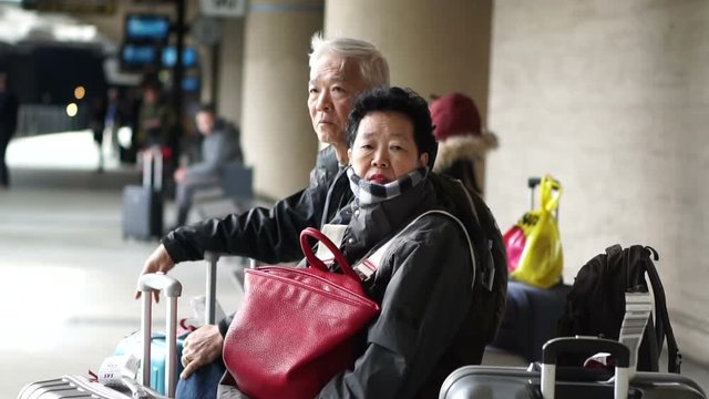 Asian senior couple with suitcases waiting for train in Europe self travel trip slow motion video