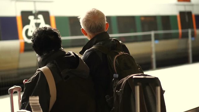 Asian senior couple with suitcases waiting for train in Europe self travel trip slow motion video