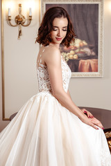 Sensual brunette bride in luxury wedding dress over classic interior, fashion beauty portrait