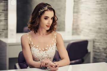 Portrait of young brunette bride woman in dressing room with wedding jewelry and dress