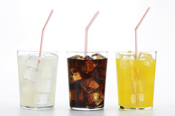 Refrescos de cola, naranja y limón en vaso con pajita sobre fondo blanco