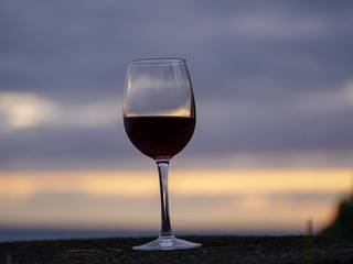 Wine bottle and glas with the sunset sky and sea in the background
