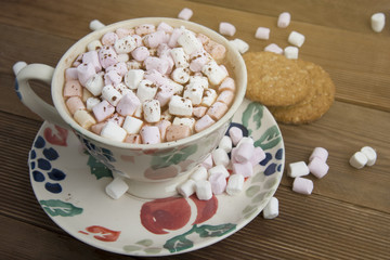 Beautiful vintage cup of homemade hot chocolate or cocoa with marshmallows and oat cookies, wooden table. Warm sweet drink