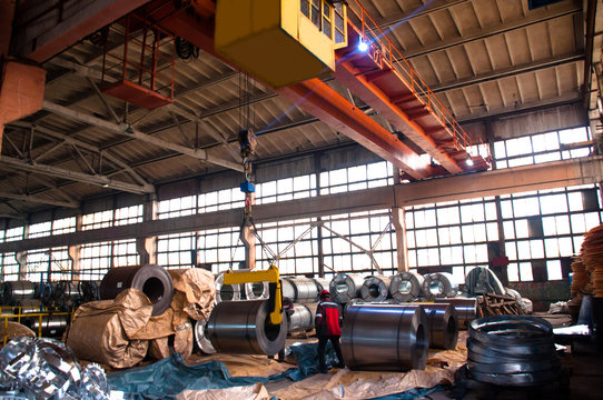 The lumberer slings a roll of galvanized steel. Warehouse of coils from galvanized steel