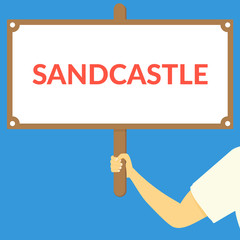 SANDCASTLE. Hand holding wooden sign