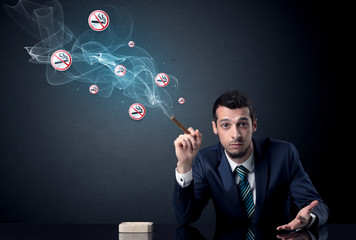 Businessman smoking with floating no smoking signs beside his head.