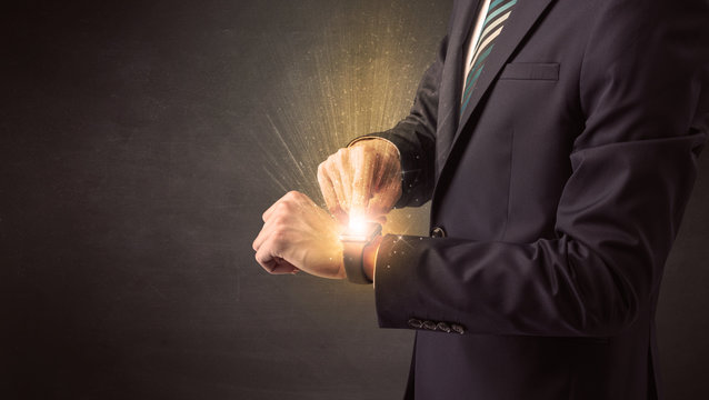 Businessman wearing smartwatch with shiny rays on it.