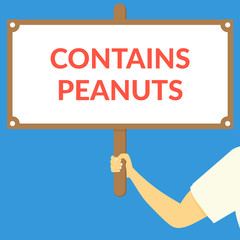 CONTAINS PEANUTS. Hand holding wooden sign