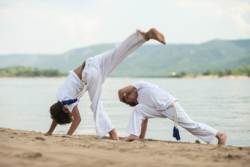 Training of two children on the beach: capoeira, sports