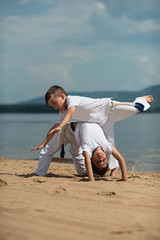 Training of two children on the beach: capoeira, sports