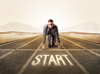 Young determined businessman kneeling before start line