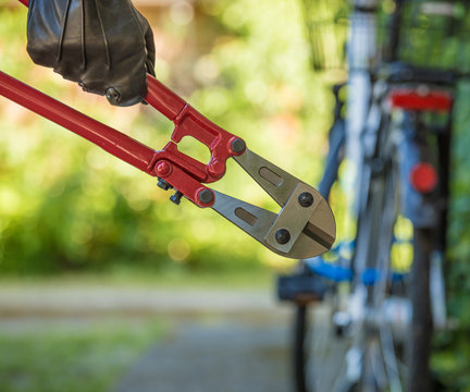 A thief holds a tool in his hand and wants to steal a bicycle