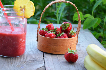 banana and strawberry smoothie in a mason jar on a wooden surface. copy space. top view