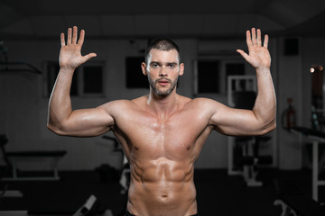 Fototapeta na wymiar Beautiful muscular man in gym posing with hands up