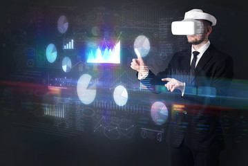 Elegant businessman in DJI goggles handling 3D reports and charts around him

