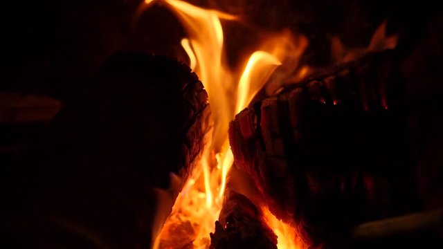 Logs on a fire are stoked in slow motion.