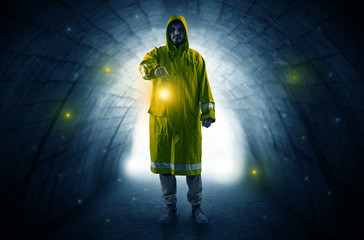 Ugly man in raincoat walking with glowing lantern in a dark tunnel
