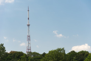 TV tower on a background of blue sky and green trees