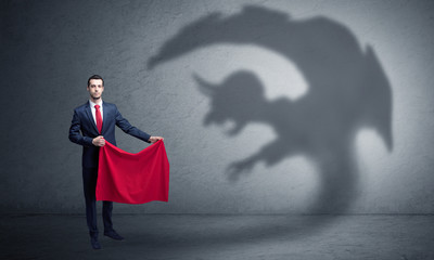 Businessman standing with red cloth in his hand and imp shadow on the background

