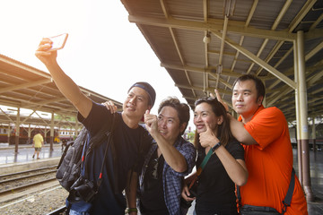 Group of four friends selfie with a smart phone in a train station in summer