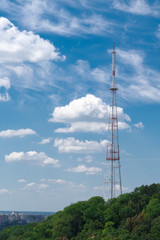 TV tower on a background of blue sky and green trees