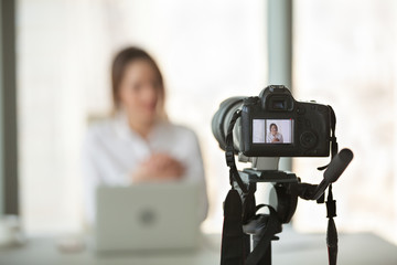 Professional video camera recording successful businesswoman giving online training or filming business course, digital device shooting vlog or interview of company boss or streaming live presentation