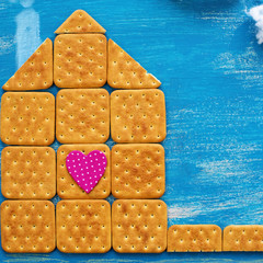 The concept of a cookie house on a wooden blue sky cloud background family path.