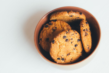 Chocolate cookies in a brown bowl on a white background, top view