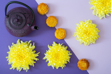 Obraz na płótnie Canvas Mooncakes, teapot, chrysanthemum flowers on duo tone background with copy space. Chinese mid-autumn festival food.