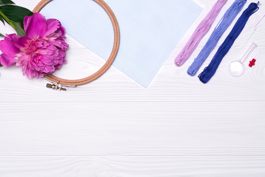 Tools for cross stitch. Threads, a hoop, a magnifier, a peony flower, a canvas