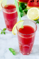 Cold watermelon lemonade with mint and lemon in glass glasses and ingredients for lemonade on a light background.