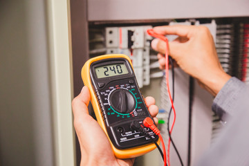 Engineer is measuring voltage or current by voltmeter in control panel