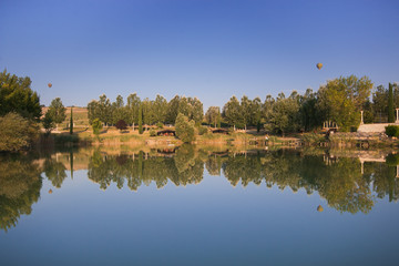 Fototapeta na wymiar Mongolfiere in volo sopra al lago del parco di Acqua Rossa in Umbria