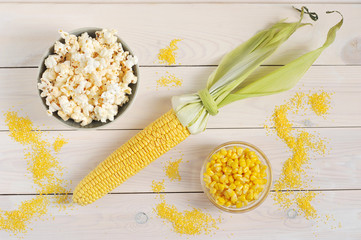 A set of corn. Corn cob, canned corn kernels, popcorn and corn croup. White wooden background....