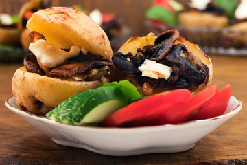 Potatoes, whole baked in oven until Golden brown, stuffed with fried onions, carrots and slices of mushrooms, decorated with sliced cucumber and tomato.