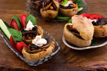 Baked in the oven with the skin of potatoes, stuffed with fried mushrooms, decorated with sour cream and sliced cucumbers and tomatoes.