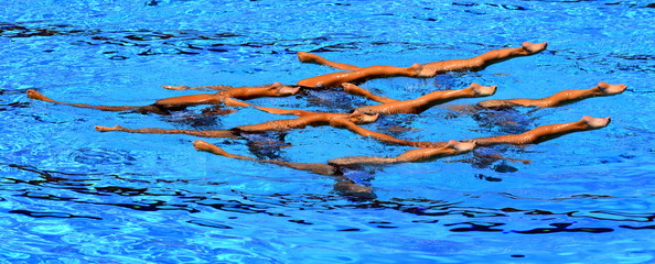 Grand jete. Synchronized swimmers legs movement. Synchronized swimming team performing a synchronized routine of elaborate moves in the water.