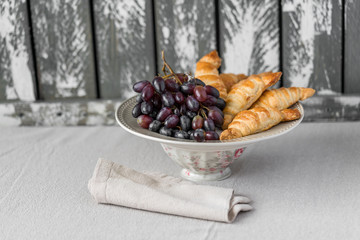 a dessert of purple grapes and homemade bread rolls on grey plate, grey colour wooden backdrop