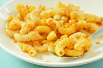 stir fried macaroni and egg with ketchup scooping in silver spoon on plate