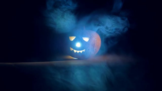 Dark room with clouds of mist and a glowing jack-o-lantern. Scary carved halloween pumpkin.