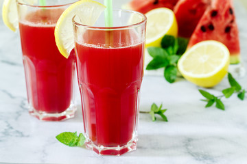 Cold watermelon lemonade with mint and lemon in glass glasses and ingredients for lemonade on a light background.