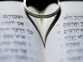 Close up of the Hebrew Jewish bible with a weeding ring creating a heart shape shadow 