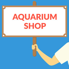 AQUARIUM SHOP. Hand holding wooden sign