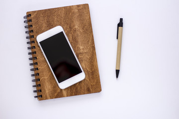 Smartphone with notebook and cup of strong coffee on wooden background. Cell phone with writing set with espresso