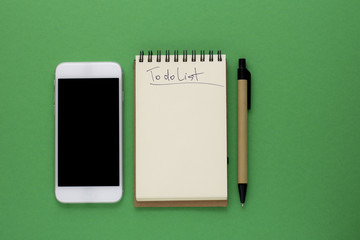 Pen,Phone and Notepad on the green background. To Do List