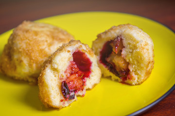 Fresh plum dumplings. One sliced dumpling and one hole on yellow plate on dark red table