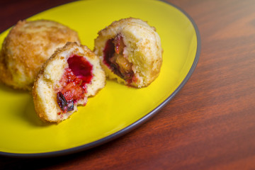 Fresh plum dumplings. One sliced dumpling and one hole on yellow plate on dark red table