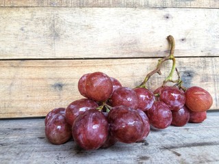 Fresh red grapes placed on brown wood.