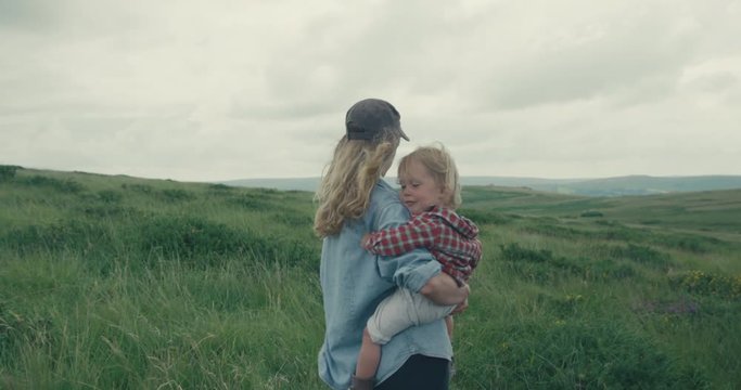 Mother standing in nature with toddler in her arms